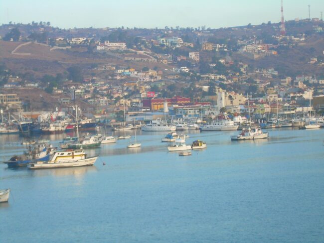 Boats moored in coastal harbor with hillside town