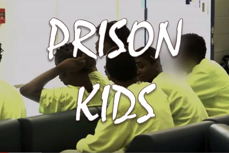 Young inmates in yellow prison uniforms sitting together.