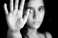 A woman with a serious expression holds up her hand as a stop gesture.