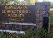 Person standing beside Minnesota Correctional Facility Shakopee sign.