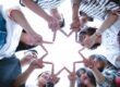 People forming a star shape with their hands while looking up.