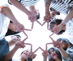 People forming a star shape with their hands while looking up. People forming a star shape with their hands while looking up.