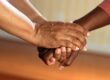 Two people holding hands in a comforting gesture.