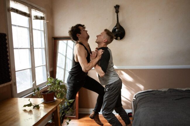 Two people dancing joyfully in a sunlit room.