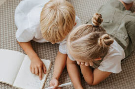 Two children reading a book together on the floor. Two children reading a book together on the floor.